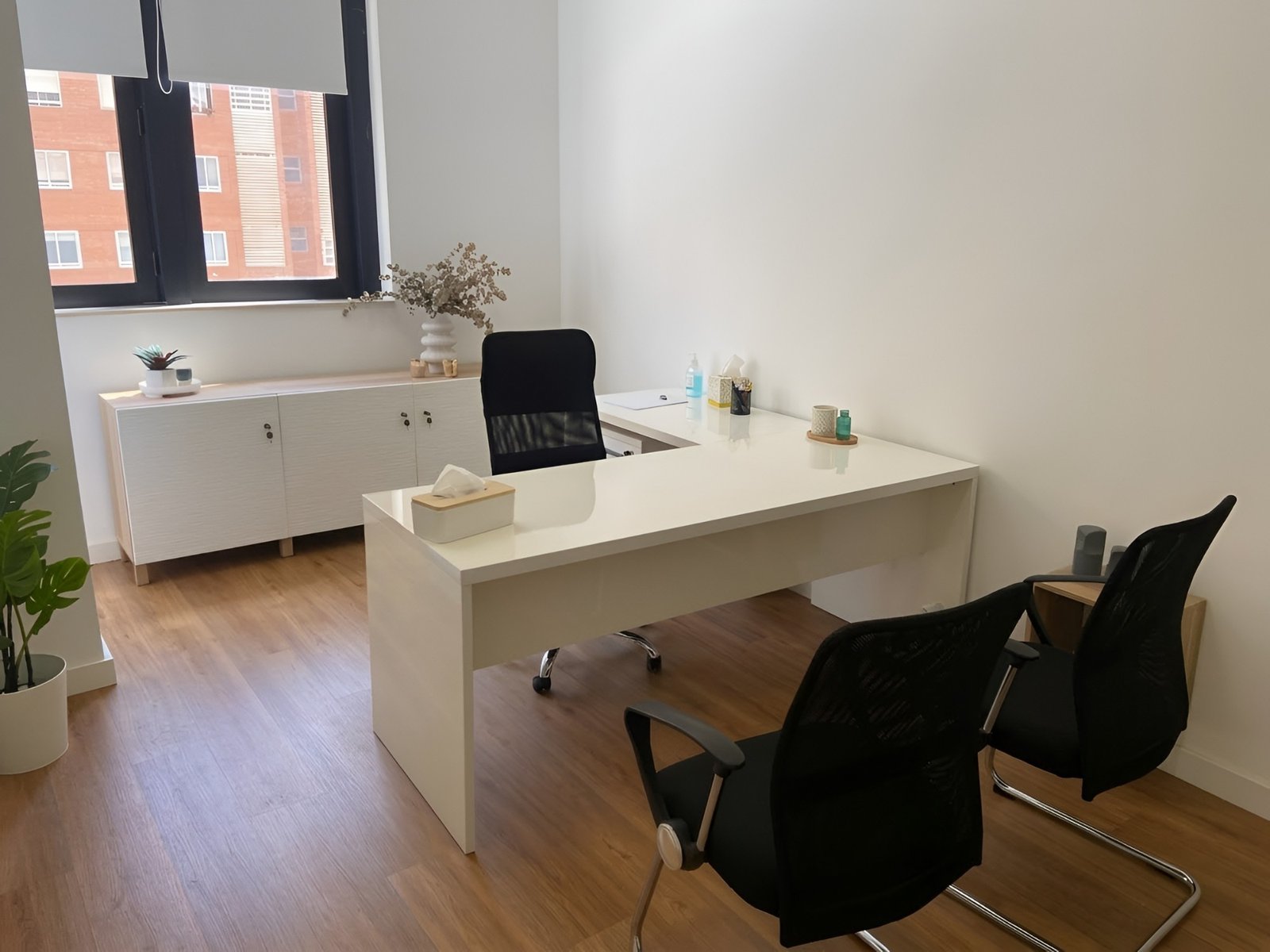 El despacho de la consulta donde trabaja Juan Tortosa en Alicante: una mesa blanca, dos sillas y una ventana con luz natural