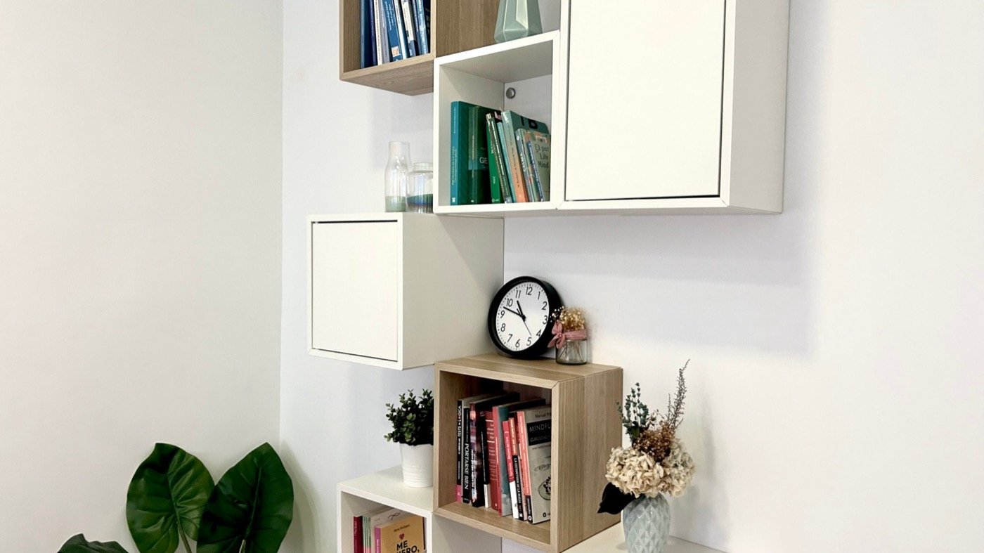 Estantería de la consulta con libros de psicología y mindfulness, un reloj y flores secas